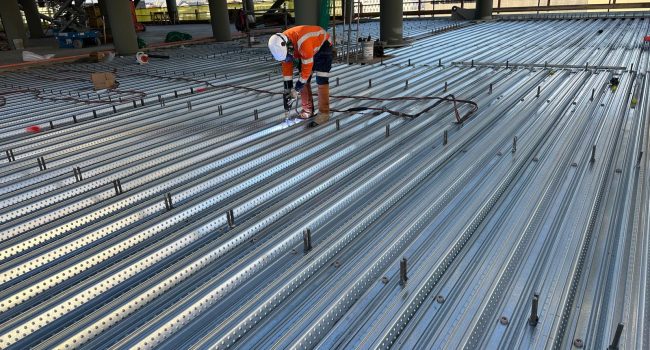 a man in orange work gear working on a metal structure